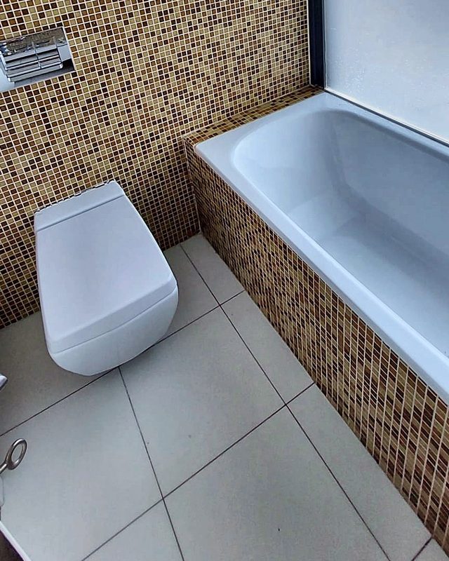 Bathroom with bathtub, mosaic tiles and wall-hung toilet