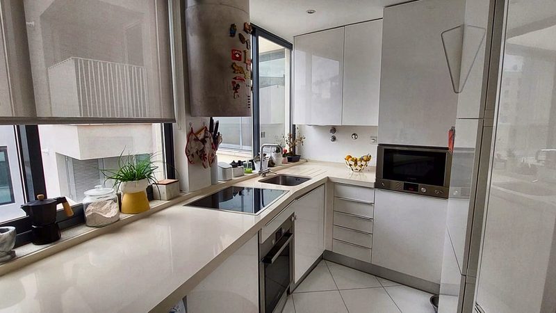 White kitchen with induction hob, oven and the sink under the window