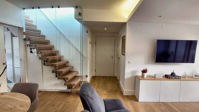 Floating staircase with glass railing next to the front door